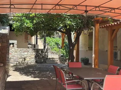a patio with a table and chairs under an umbrella at Maison de caractère CASA LECA, piscine privée chauffée in Feliceto