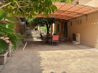 a patio with a table and chairs under a pergola at Maison de caractère CASA LECA, piscine privée chauffée in Feliceto