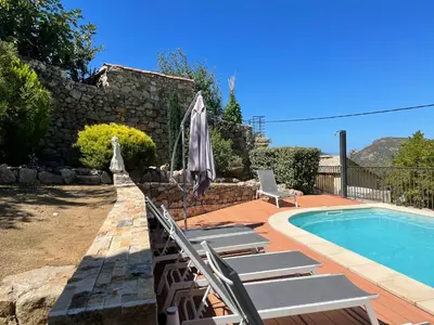 a pool with chairs and an umbrella next to a house at Maison de caractère CASA LECA, piscine privée chauffée in Feliceto