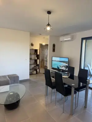 a dining room with a glass table and black chairs at L'Immortelle - T3 avec balcon vue mer & montagne in Calenzana