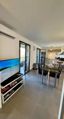 a living room with a dining table and a television at L'Immortelle - T3 avec balcon vue mer & montagne in Calenzana