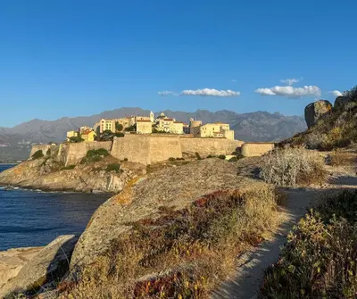 a castle on a hill next to the water at L'Immortelle - T3 avec balcon vue mer & montagne in Calenzana