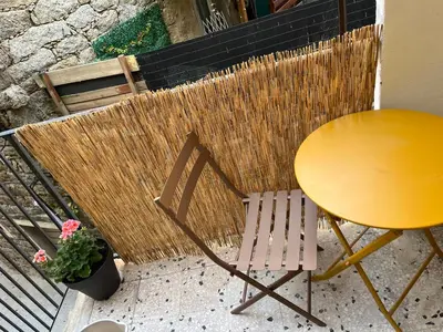 a yellow table and a chair next to a table and a plant at Appartement dans le coeur de Sartène, la plus corse des villes corses in Sartène