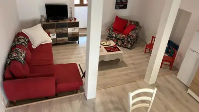 a living room with a red couch and a chair at Appartement dans le coeur de Sartène, la plus corse des villes corses in Sartène