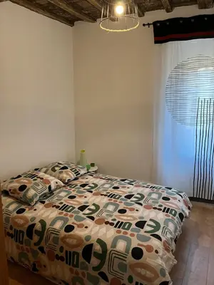 a bedroom with a bed with a comforter and a window at Appartement dans le coeur de Sartène, la plus corse des villes corses in Sartène