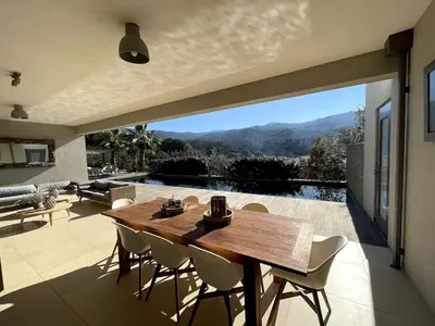 a wooden table and chairs on a patio with a view at La Villa K, plage du Ruppione in Pietrosella