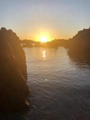 a sunset over a body of water with rocks at La Villa K, plage du Ruppione in Pietrosella