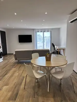 a living room with a table and chairs and a couch at Rez de villa Proche d'Ajaccio in Sarrola-Carcopino