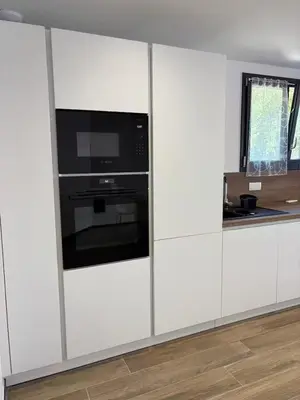 a kitchen with white cabinets with a microwave and a appliance at Rez de villa Proche d'Ajaccio in Sarrola-Carcopino