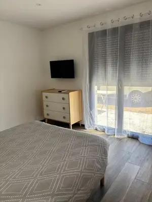 a bedroom with a bed and a dresser with a television at Rez de villa Proche d'Ajaccio in Sarrola-Carcopino