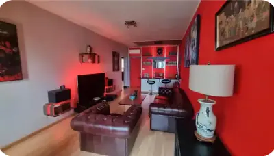 a living room with red walls and leather furniture at Spacieux T2 route des sanguinaires in Ajaccio