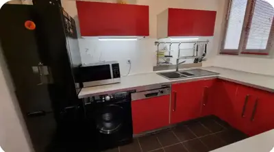 a kitchen with red cabinets and a black refrigerator at Spacieux T2 route des sanguinaires in Ajaccio