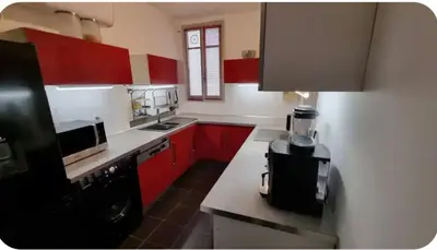 a kitchen with red cabinets and a black appliance at Spacieux T2 route des sanguinaires in Ajaccio