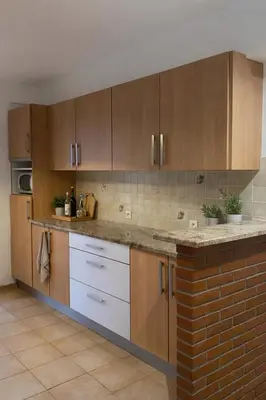 a kitchen with wooden cabinets and a brick wall at Lumineux T3 avec double terrasse au calme - parking sécurisé in Ajaccio