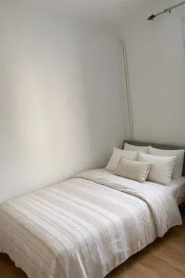 a bed in a room with a white wall at Lumineux T3 avec double terrasse au calme - parking sécurisé in Ajaccio