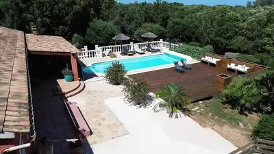 an overhead view of a swimming pool with a wooden deck at Villa 140 m2 avec piscine, parc privatif 5000m2 à Bonifacio-Porto Vecchio in Bonifacio