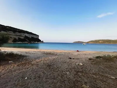 a sandy beach with a boat in the water at Villa 140 m2 avec piscine, parc privatif 5000m2 à Bonifacio-Porto Vecchio in Bonifacio