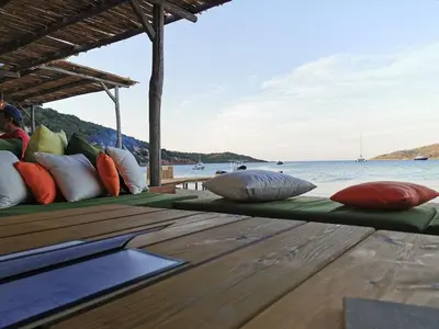 a group of pillows sitting on a deck next to the water at Villa 140 m2 avec piscine, parc privatif 5000m2 à Bonifacio-Porto Vecchio in Bonifacio