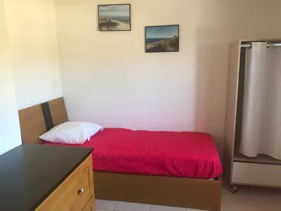 a small bedroom with a red bed and a refrigerator at Villa A Nuciola - Prunete in Cervione