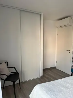 a bedroom with a bed and a chair and a sliding door at L'Immortelle in Zonza