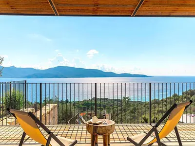 a balcony with two chairs and a table and the ocean at Villa Paolina in Olmeto