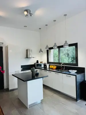 a kitchen with white cabinets and a black counter top at Casa Caseddu, Heated pool, 4 people, Bonifacio in Bonifacio