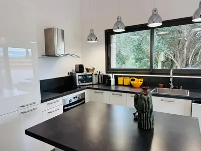 a kitchen with white cabinets and a black counter top at Casa Caseddu, Heated pool, 4 people, Bonifacio in Bonifacio