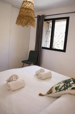 a dining room with a wooden table and white chairs at Bergerie avec piscine à Sotta vue maquis in Sotta