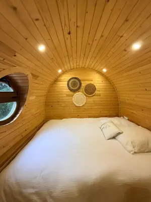 a bed in a room with a wooden ceiling at Roulotte Atypique - Vue Mer - Écrin de Nature in Cauro