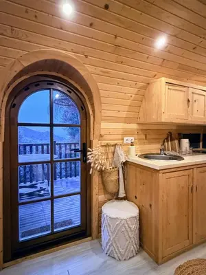 a kitchen with a large window in a wooden cabin at Roulotte Atypique - Vue Mer - Écrin de Nature in Cauro