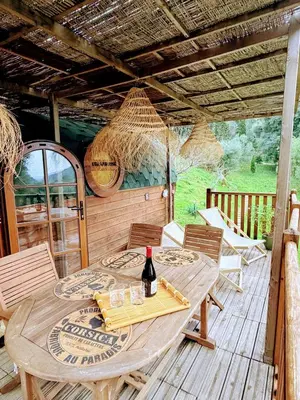 a wooden table with a bottle of wine on a deck at Roulotte Atypique - Vue Mer - Écrin de Nature in Cauro