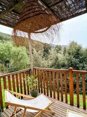 a wooden deck with a chair and an umbrella at Roulotte Atypique - Vue Mer - Écrin de Nature in Cauro