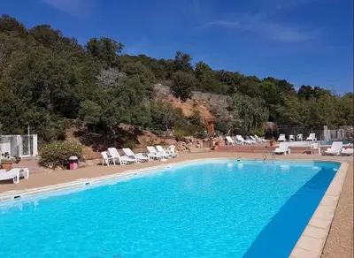 a large swimming pool with lounge chairs and a mountain at Casa di Piero e Anna in Porto-Vecchio