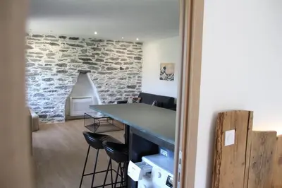 a room with a stone wall and a table with stools at Casa di a Volpe in Corte