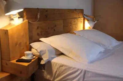 a bed with a wooden headboard with a cup and a lamp at Casa di a Volpe in Corte
