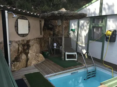 a house with a pool with a chair and an umbrella at Chalet stella in Olmeto