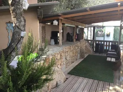 a patio with a stone wall and a wooden deck at Chalet stella in Olmeto