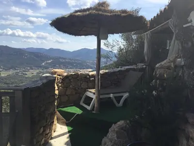 a bench with an umbrella on a stone wall at Chalet stella in Olmeto