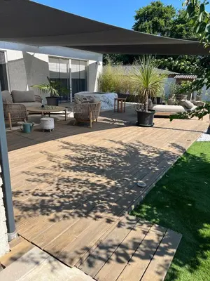 a backyard with a wooden deck with a black umbrella at Maison de charme entre mer et nature 4pers in Cervione