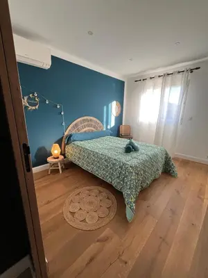 a bedroom with a bed with a blue wall at Maison de charme entre mer et nature 4pers in Cervione