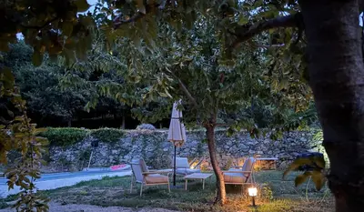 a table and chairs with an umbrella and a candle at Suite avec jardin et piscine in Murato