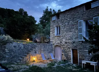 a group of chairs sitting outside of a stone building at Suite avec jardin et piscine in Murato
