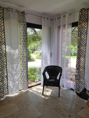 a chair sitting in front of a window with curtains at U ghjosu rossu, Maison indépendante, bien située in Appietto