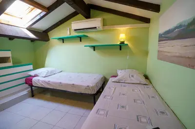 two beds in a room with green walls and a window at A nostra casetta corsa, Carina, en bord de mer in Ghisonaccia
