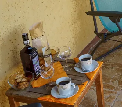 a table with a bottle of wine and two cups of coffee at A nostra casetta corsa, Carina, en bord de mer in Ghisonaccia