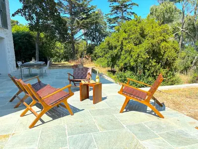 three wooden chairs and a table on a patio at L'appartement Vinosa in Aléria