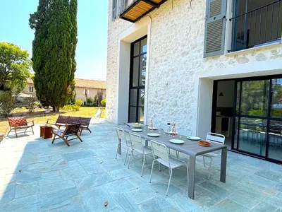 a stone patio with a table and chairs on it at L'appartement Vinosa in Aléria