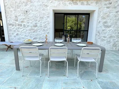 a gray table with four white chairs around it at L'appartement Vinosa in Aléria