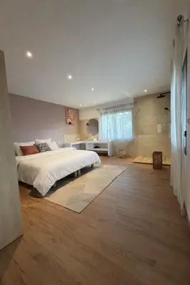 a bedroom with a large white bed and wooden floors at Maison de campagne in Sartène