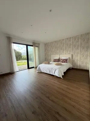 a bedroom with a large bed and a large window at Maison de campagne in Sartène